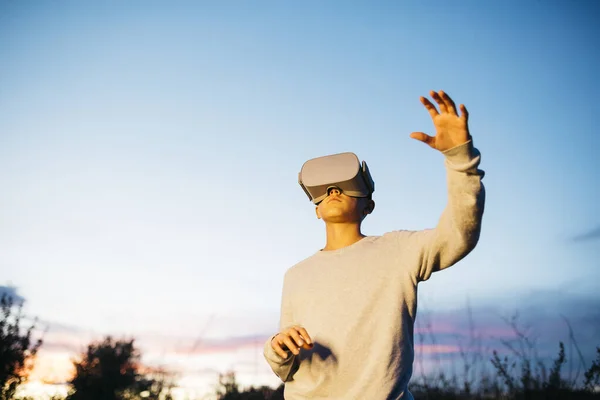 Boy Wearing Virtual Reality headset simulator on a countryside