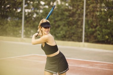 Genç ve güzel bir kadın tenis oynuyor. Sporcu kadın arkadaşlarıyla tenis oynarken eğleniyor..