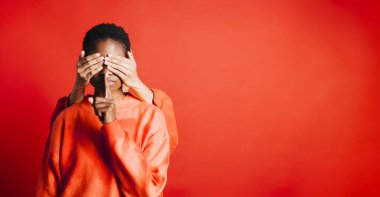 Gözleri başka bir kadının elleriyle kaplanmış genç bir kadının portresi ve dudaklarında bir parmakla sessizlik hareketi yapıyor..