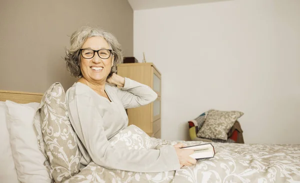 Porträtt Äldre Kvinna Som Sitter Sängen Med Pyjamas Och Läser Stockfoto