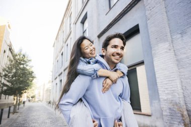 Kız arkadaşını sırtında taşıyan genç bir adam şehir caddesinde yürüyor. Şehir caddesinde bir çift geziyor..