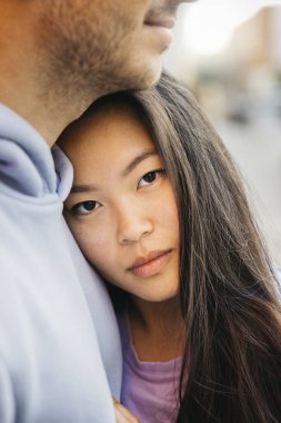 Erkek arkadaşını kucaklayan genç ve güzel Asyalı bir kadının yakın portresi..