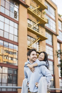 Kız arkadaşını sırtında taşıyan genç bir adam şehir caddesinde yürüyor. Şehir caddesinde bir çift geziyor..