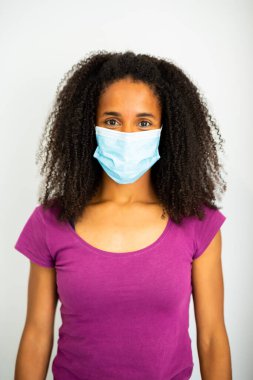Afro saçlı, mavi cerrahi maske takan ve mor gömlekli bir kadının portresi..