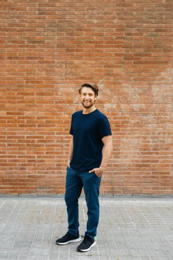 Duvara dayanmış genç bir adamın portresi. Elleri cebinde güvenle gülümsüyor. Sıradan giyinmiş, rahat ve cana yakın görünüyor..