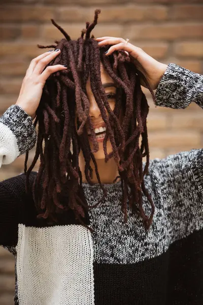 stock image Woman smiling gently and playing with her dreadlocks framing her face.