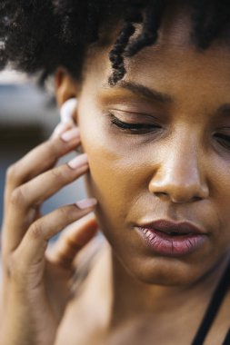 Kablosuz kulaklıklarını ayarlayan bir kadının yakın çekimi. Çalışmaya hazırlanan konsantre bir kadının portresi..