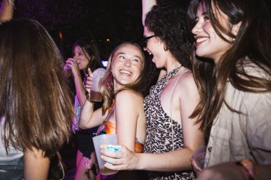 Bir gece kulübünde dans eden ve gülen bir grup neşeli genç kadın..