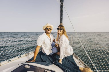 Neşeli bir çift, bir yelkenlide güneşlenirken etrafları okyanuslarla çevrili, kaygısız bir yaz macerasının özünü yakalıyorlar..
