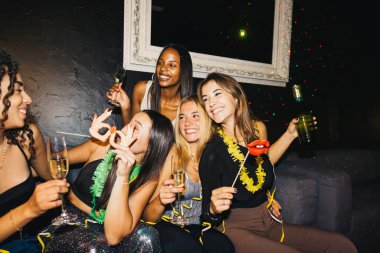 Bir gece kulübünde kutlama yapan neşeli bir arkadaş grubu. Şenlikli bir atmosferde şampanya ve aksesuar tutuyorlar ve kahkahalarla dolular..