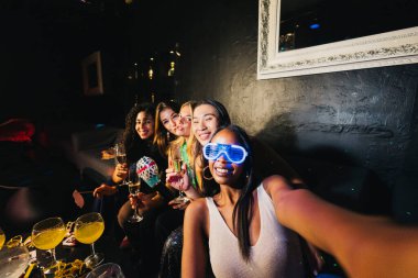 İçkiler ve kahkahalarla coşkulu bir gece geçirirken selfie çeken bir grup genç kadın, neşeli bir atmosferde unutulmaz anlar yakalıyorlar..