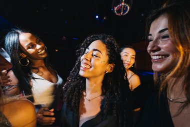 Neşeli bir grup genç kadın neşeli bir partide birlikte dans edip eğleniyorlar..