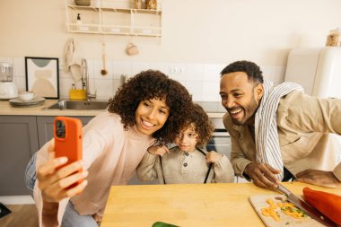 Akıllı telefonlarıyla telefon görüşmesi yapan neşeli bir aile mutfaklarında vakit geçiriyorlar. Sahne, aile üyeleri arasında paylaşılan neşeli ve yakın bağın altını çiziyor.