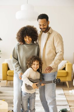 Ailelerin ve çocukların oturma odalarında gitar çalarken eğlendikleri neşeli bir aile anı..