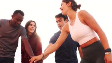 Çeşitli arkadaş grubunun düşük açılı çekimi neşeyle ellerini birleştirip birlik ve takım çalışmasını sembolize ediyor..