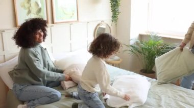 Neşeli aile yatak odalarında yastık kavgası yaparak eğleniyor. Kahkaha dolu..