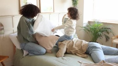 Neşeli aile yatak odalarında yastık kavgası yaparak eğleniyor. Kahkaha dolu..