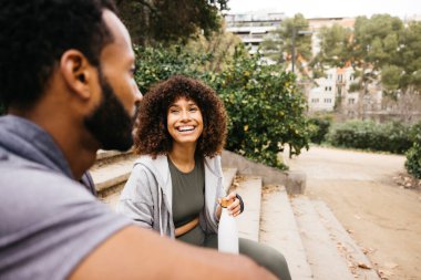 İki arkadaş, idmandan sonra şehir parkının merdivenlerinde oturup sohbet etmekten zevk alıyorlar..
