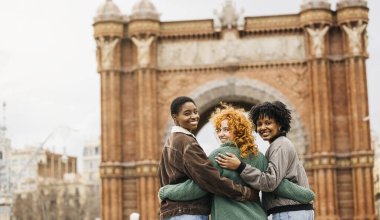 Üç kadın turist sarılıyor, Barselona, İspanya 'daki Arc de Triomf' u ziyaret ediyorlar