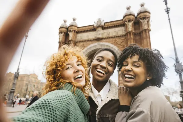Barcelona, İspanya 'da üçlü kavşağın önünde selfie çeken üç mutlu kadın turist.