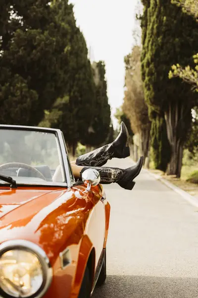 Araba yolculuğundan hoşlanan bir kadın ayaklarını üstü açık bir arabanın camından içeri sokuyor.