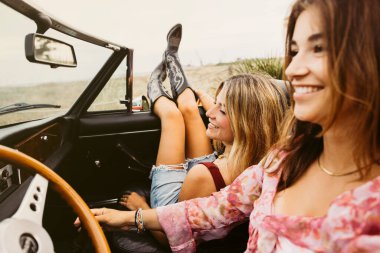 İki mutlu arkadaş eski model üstü açık arabayla yaz yolculuğunun keyfini çıkarıyorlar.
