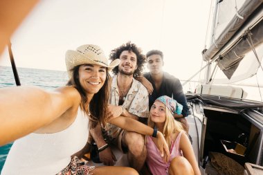 Dört mutlu arkadaş güneşli bir günde okyanusta yelken açıp selfie çekiyorlar.