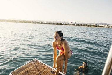 Mutlu turistler yaz tatillerinin tadını çıkarıyorlar. Denizde ferahlatıcı bir yüzüşten sonra gemiye geri dönüyorlar.