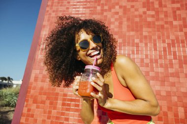 Mutlu bir turist, güneşli bir yaz gününde plajda ferahlatıcı bir meyve suyu içiyor.