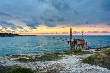 Vieste, İtalya. San Lorenzo Körfezi 'nde gün batımında Trabucco manzarası. Trabucco, İtalya 'nın güneyindeki Abruzzo ve Puglia bölgelerine özgü eski bir balıkçılık makinesidir. 4 Eylül 2022.