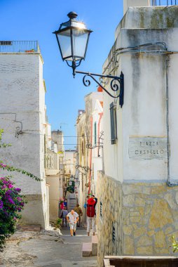 Vieste, İtalya. Şehrin tarihi merkezinde, Piazza Castello yakınlarında, bir yaz günü karakteristik dar bir caddenin manzarası. Dikey görüntü. 5 Eylül 2022.