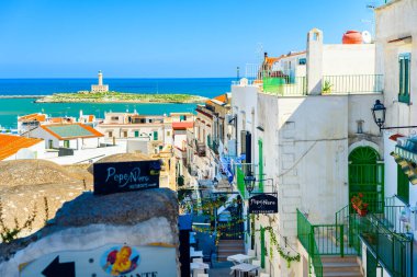 Vieste, İtalya. Via Cesare Battisti 'den kasaba manzarası. Uzakta Vieste 'nin deniz feneri. 5 Eylül 2022.