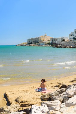 Vieste, İtalya. Lungomare Cristoforo Colombo plajının manzarası. Uzakta San Francesco Kilisesi. Dikey görüntü. 5 Eylül 2022.