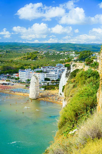Vieste, İtalya. Lungomare Enrico Mattei plajının tepesinden panoramik manzara ünlü Pizzomunno Monolith denize yükseliyor. Dikey görüntü. 5 Eylül 2022.