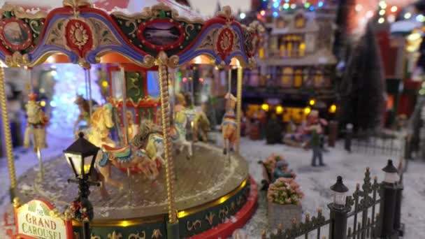 Detailní Pohled Vánoční Vesničku Miniatura Kolotočem Pohyblivými Koňmi Světly Sněhem — Stock video