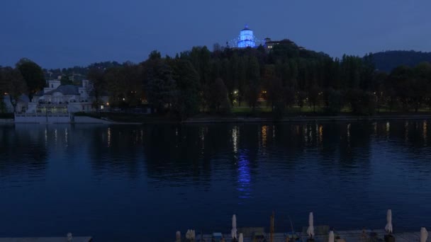 イタリア トリノ サンタ マリア モンテ カップチーニ教会の夜に青い光に照らされて眺めます 手前のポー川 リアルタイムビデオ 2022年10月29日 — ストック動画