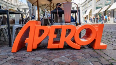 Torino, İtalya. Caddedeki kafedeki masaların yakınındaki Aperol marka tabela. 2023-10-21.