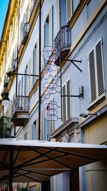Torino, İtalya. Şehir merkezindeki bir binanın ön cephesinde 'CAFE' kelimesinin neon ışıklarıyla imzalayın. Dikey görüntü. 2023-10-21.