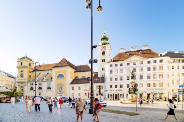 Viyana, Avusturya. Bir yaz öğleden sonrasında Freyungplatz. Soldaki Schottenkirche. Bazı insanlar sokakta geziniyor. 2023-08-02.