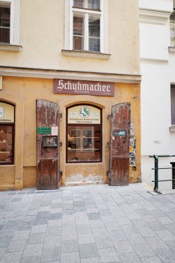 Viyana, Avusturya. Naglergasse 'de tahta kepenkleri ve klasik tarzı tabelası olan antika bir ayakkabı imalatçısının cephesi. Dikey görüntü. 2023-08-02.