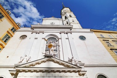 Viyana, Avusturya. Michaelerplatz 'daki St. Michaelis Kilisesi cephesi. Girişin üstünde San Michele 'e adanmış bir heykel var. Sağdaki çan kulesi. 2023-08-02.