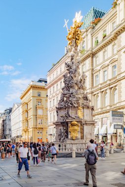 Vienna, Austria. Trinity column carved in the late 17th century in memory of the plague victims in Graben street, with some tourists and citizens on the street. Vertical image. 2023-08-02. clipart