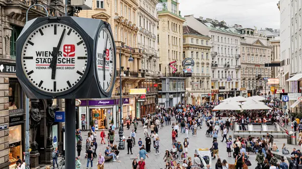 Viyana, Avusturya. Stock-im-Eisen-Platz Meydanı 'nın yukarısı insan ve turistlerle dolu. Şehir merkezindeki alışveriş alanında. Ön planda dört düğmeli bir sokak saati var. 2023-08-03.