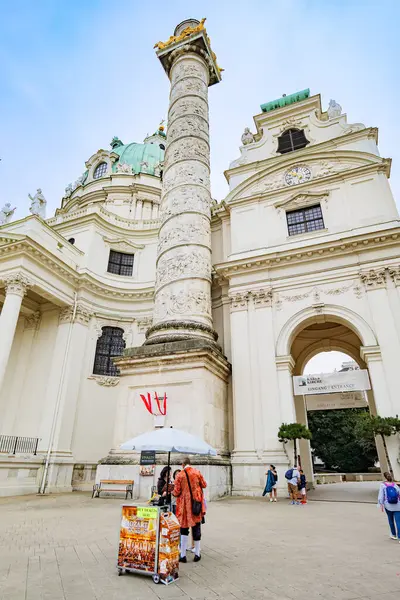 奥地利 维也纳 卡尔斯普拉斯的圣查尔斯教堂景观 柱子上装饰有浮雕 立面装饰有钟表 雕像和穹顶 教堂外的一些人垂直图像 2023 — 图库照片