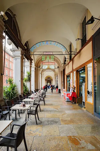 stock image Turin, Italy. View of the arcades of Via Cernaia, with the neon signs of the shops. Some people on the street. Vertical image. 2024-05-26.