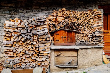 Pontechianle, İtalya. Bir dağ evinin duvarına istiflenmiş tahta kütükler. Depolama araçları için minyatür ahşap ev.