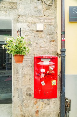 Bolsena, Italy. Red Italian postal mailbox on the wall of a building in the city center. Vertical image. 2024-06-21. clipart