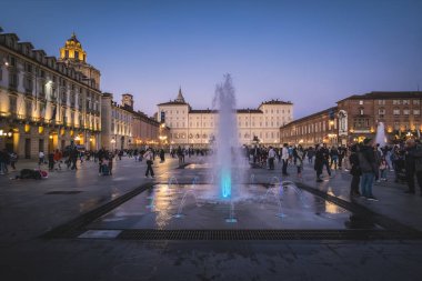 Torino, İtalya. Akşamları Piazza Castello 'da su sıçrayan ve renkli su oyunları. Kraliyet Müzeleri 'nin ana cephesi. Etrafta bir sürü insan var. 2024-11-02.
