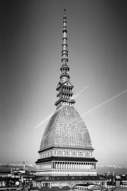 Torino, İtalya. Ulusal Sinema Müzesi 'nin evi Köstebek Antonelliana' nın yarı boy görüntüsü. Güneşli bir kış gününde binaların çatıları, karla kaplı Alpler. Siyah ve beyaz dikey görüntü. 2025-02-15.
