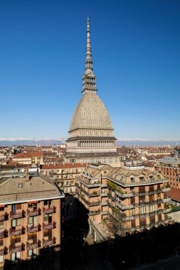 Torino, İtalya. Ulusal Sinema Müzesi 'nin evi Köstebek Antonelliana' nın yarı boy görüntüsü. Güneşli bir kış gününde binaların çatıları, karla kaplı Alpler. Dikey görüntü. 2025-02-15.